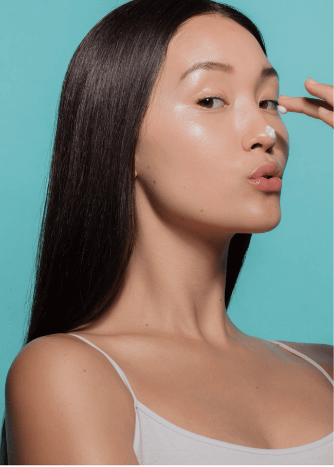 Asian girl applying cream on nose