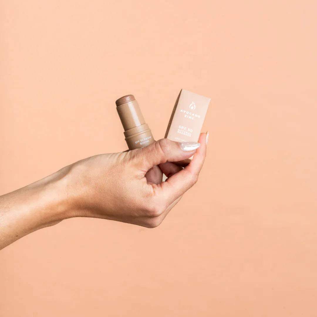 Hand holding Avocado Zinc SPF 50 Natural Bronzer against a light background