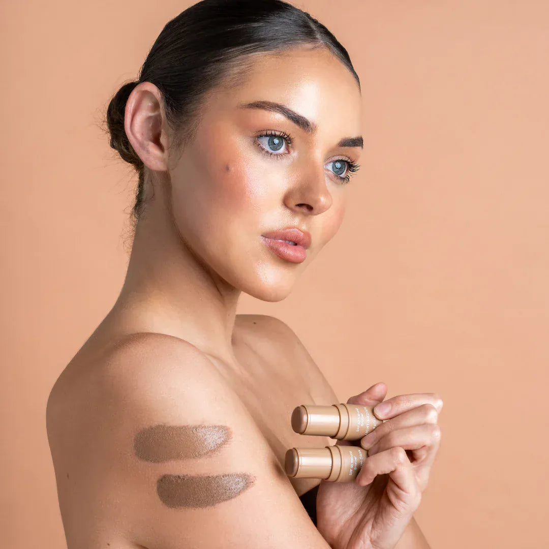 Woman holding Avocado Zinc SPF 50 Natural Bronzer with swatches on arm for sun protection and natural glow.