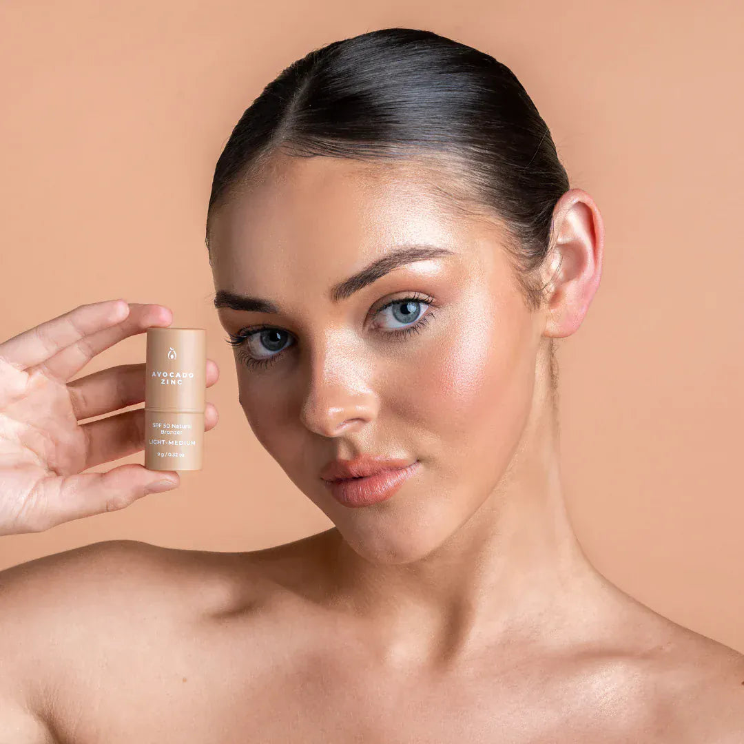 Woman holding Avocado Zinc SPF 50 Natural Bronzer with glowing skin