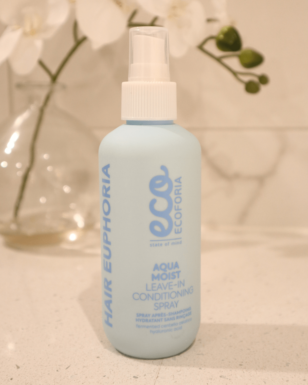 Ecoforia Aqua Moist Leave-In Conditioner Spray (200ml) on bathroom vanity, providing hydration and protection for hair without rinsing.