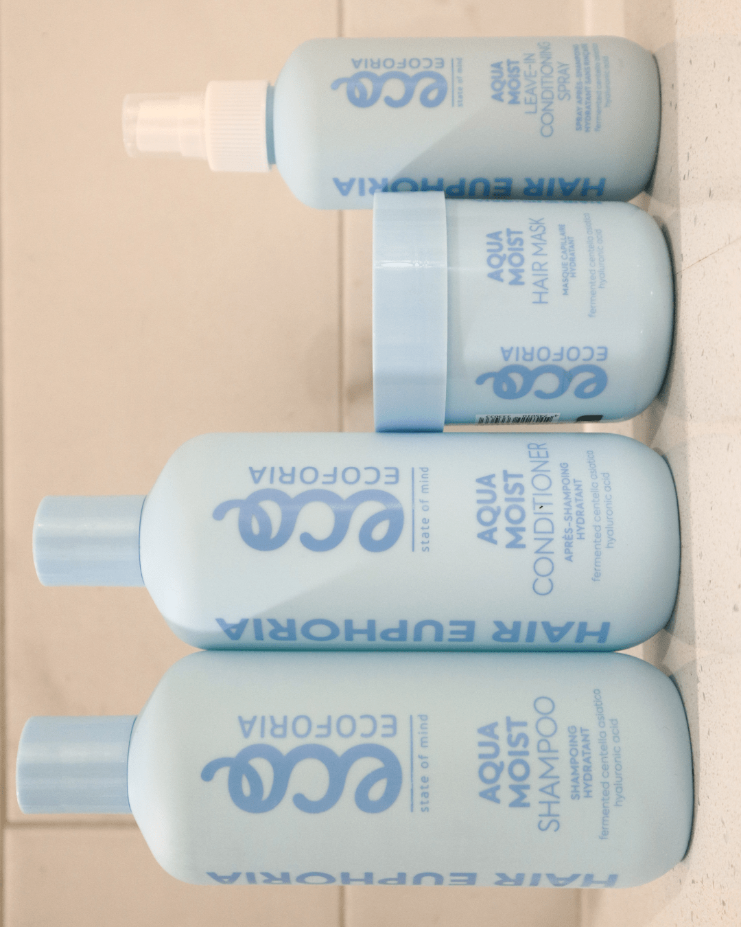 Ecoforia Aqua Moist Leave-In Conditioner Spray and haircare products arranged together on a surface.