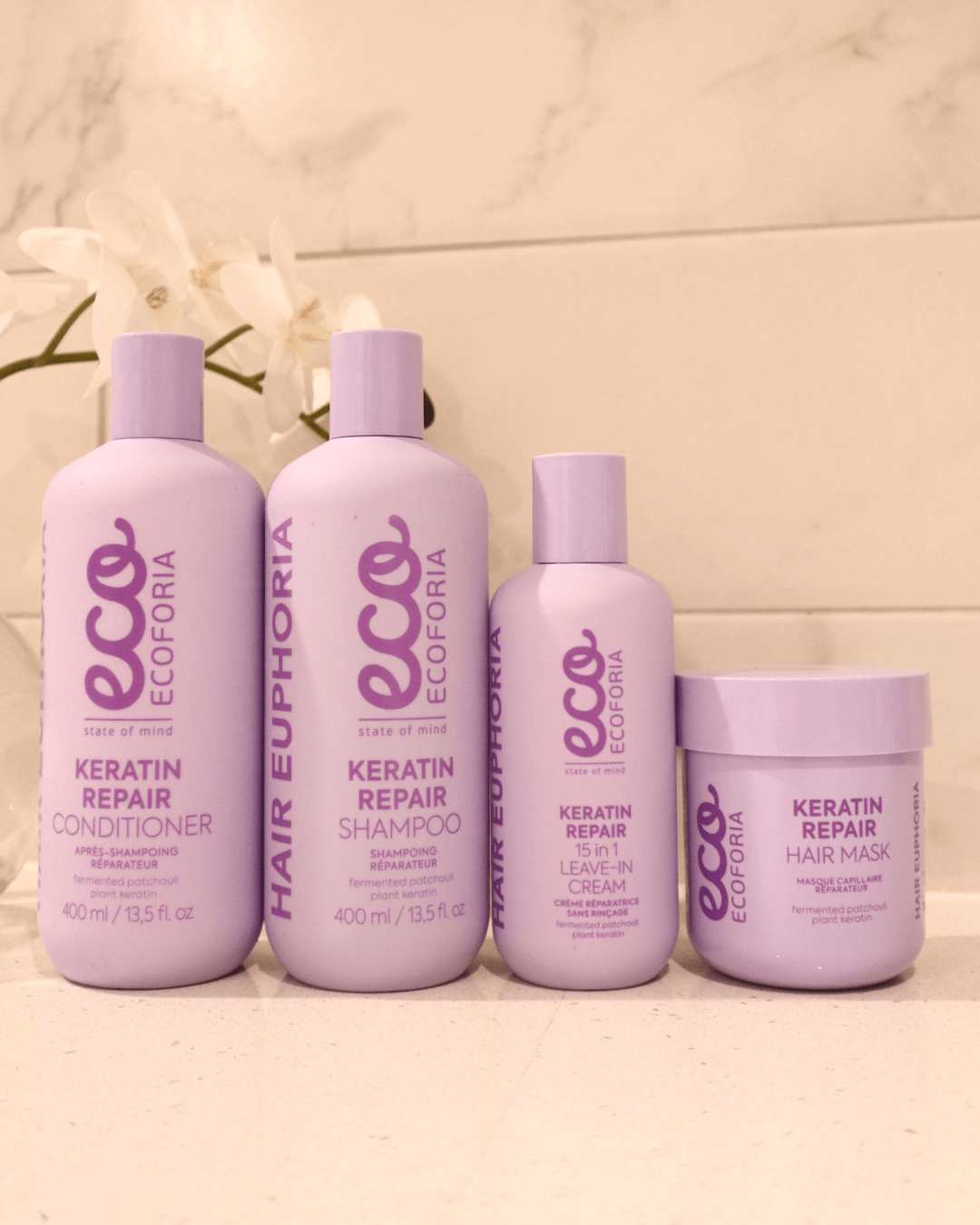Ecoforia Keratin Repair Hair Mask 200ml with shampoo, leave-in cream, and conditioner on a bathroom counter.