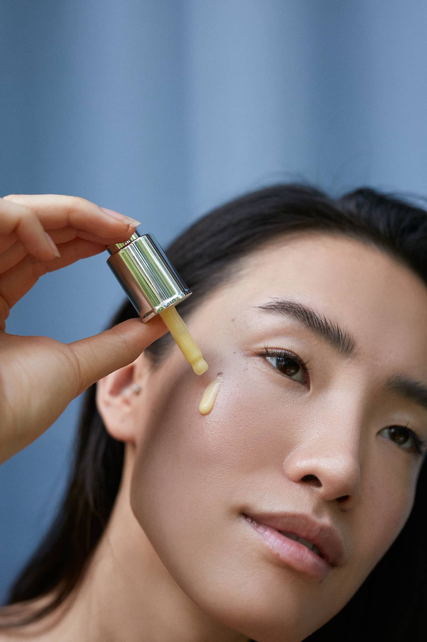 Woman applying Gracious Minds Nectar Firming Eye Serum Elixir to her skin