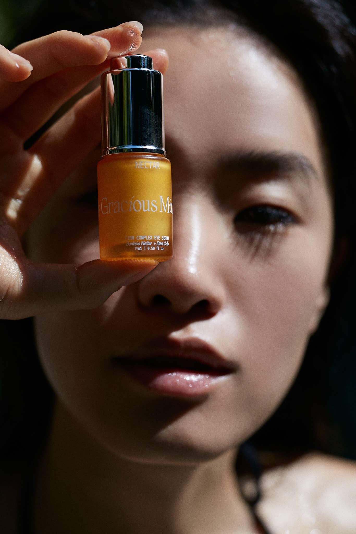 Person holding Gracious Minds Nectar Firming Eye Serum Elixir 15ml, highlighting skincare benefits.