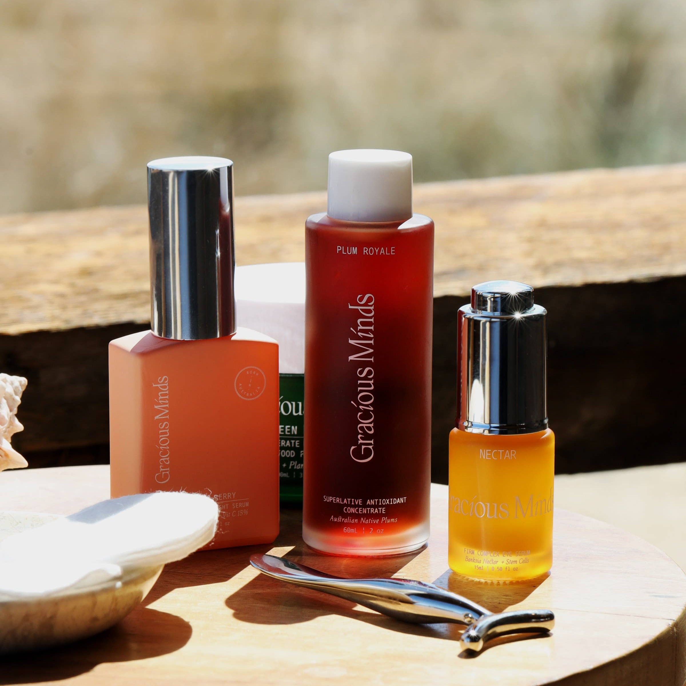 Gracious Minds Plum Royale Superlative Antioxidant Concentrate with other skincare products on wooden surface