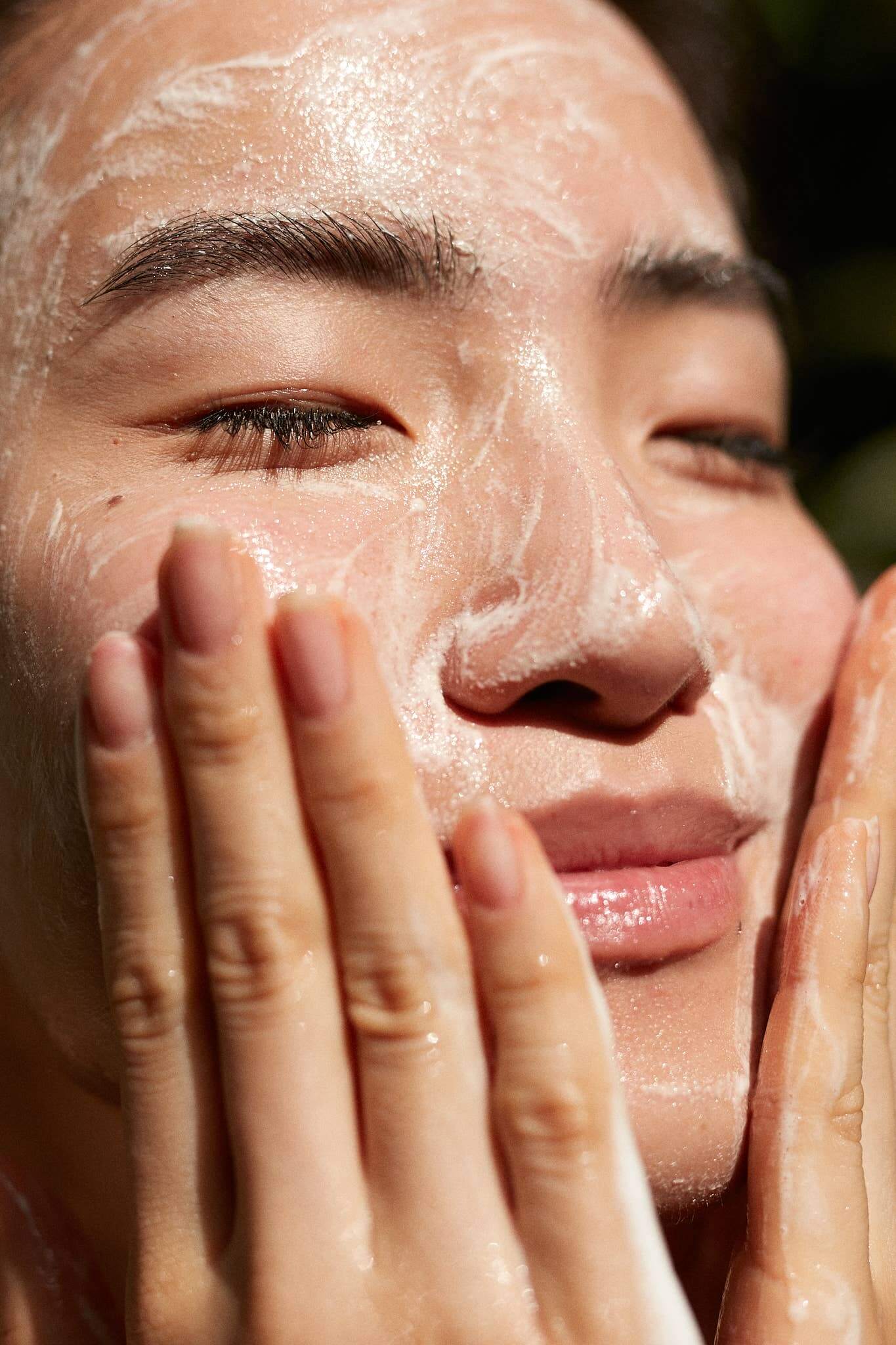 Woman applying Gracious Minds Young Grass Purifying Gel Cleanser for a refreshing, gentle face wash focusing on impurities and balance.
