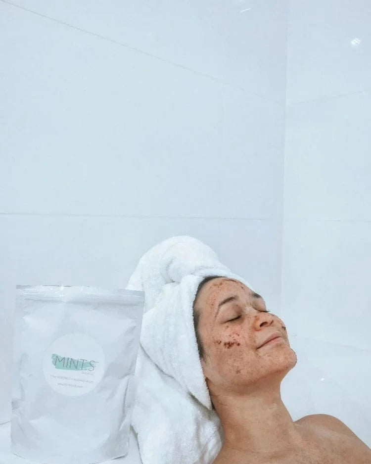 Mint.s Face Scrub used by a woman with a towel, enjoying a relaxing skincare routine in a bright bathroom.