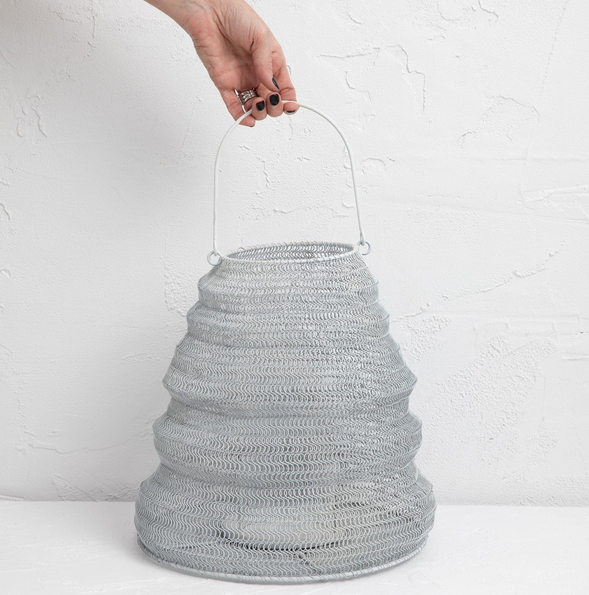 Hand holding a Mesh Lanterns White textured iron decorative lighting piece for soft glow and unique décor.