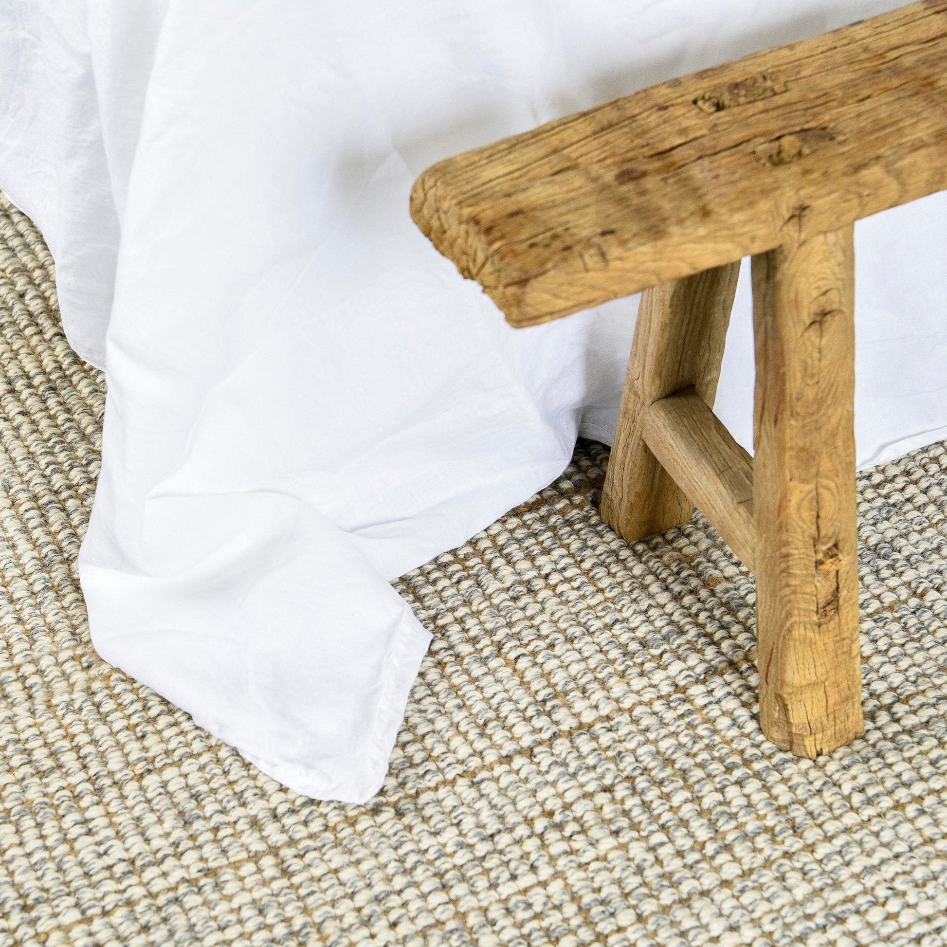 Jute Wool Rugs & Runners natural texture under a cozy blanket with a wooden stool.
