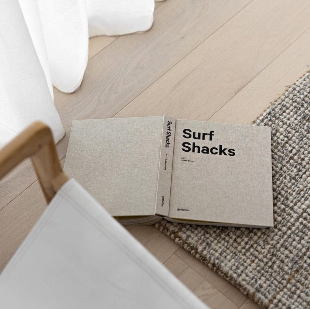 Open book titled 'Surf Shacks' on natural Jute Wool Rugs & Runners, showcasing cozy home decor.