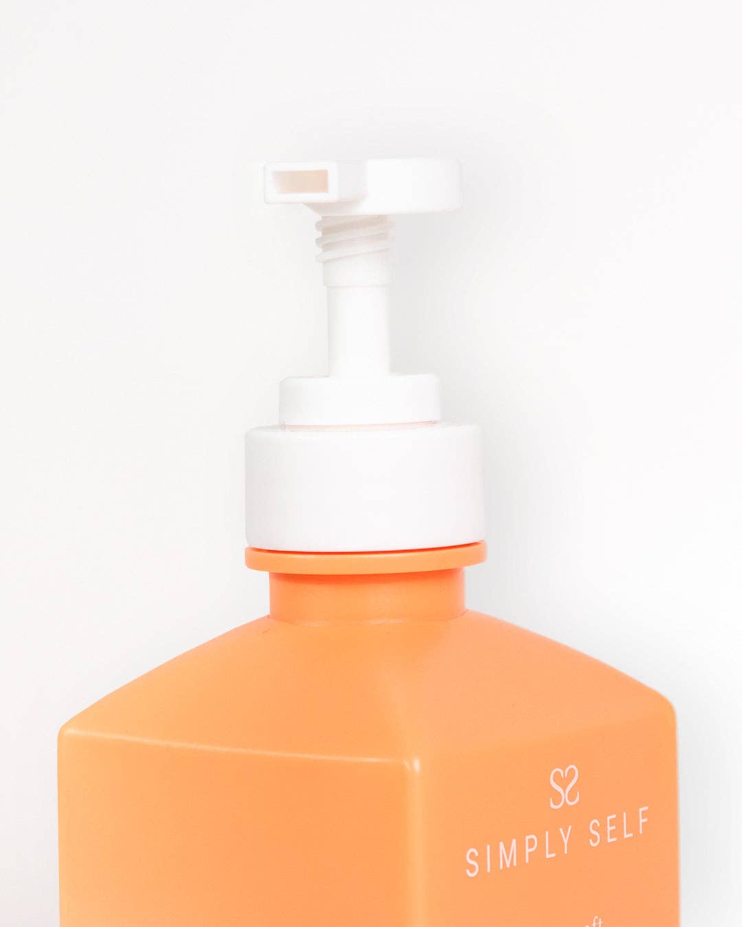 Pump bottle from Simply Self Glow Essential Body Bundle with orange design for nourishing skin care.