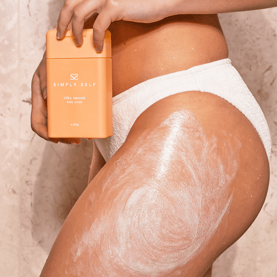 Close-up of Simply Self Silky Smooth Body Scrub being applied to leg, showing exfoliating treatment for softer, smoother skin.