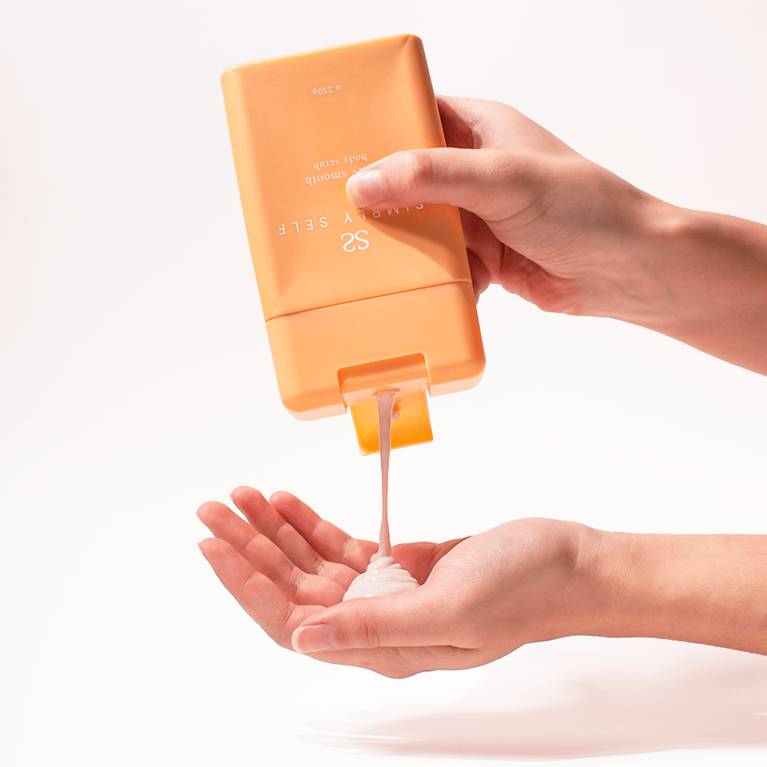 Simply Self Silky Smooth Body Scrub 250g being dispensed into a person's hand, showcasing its texture and packaging design.