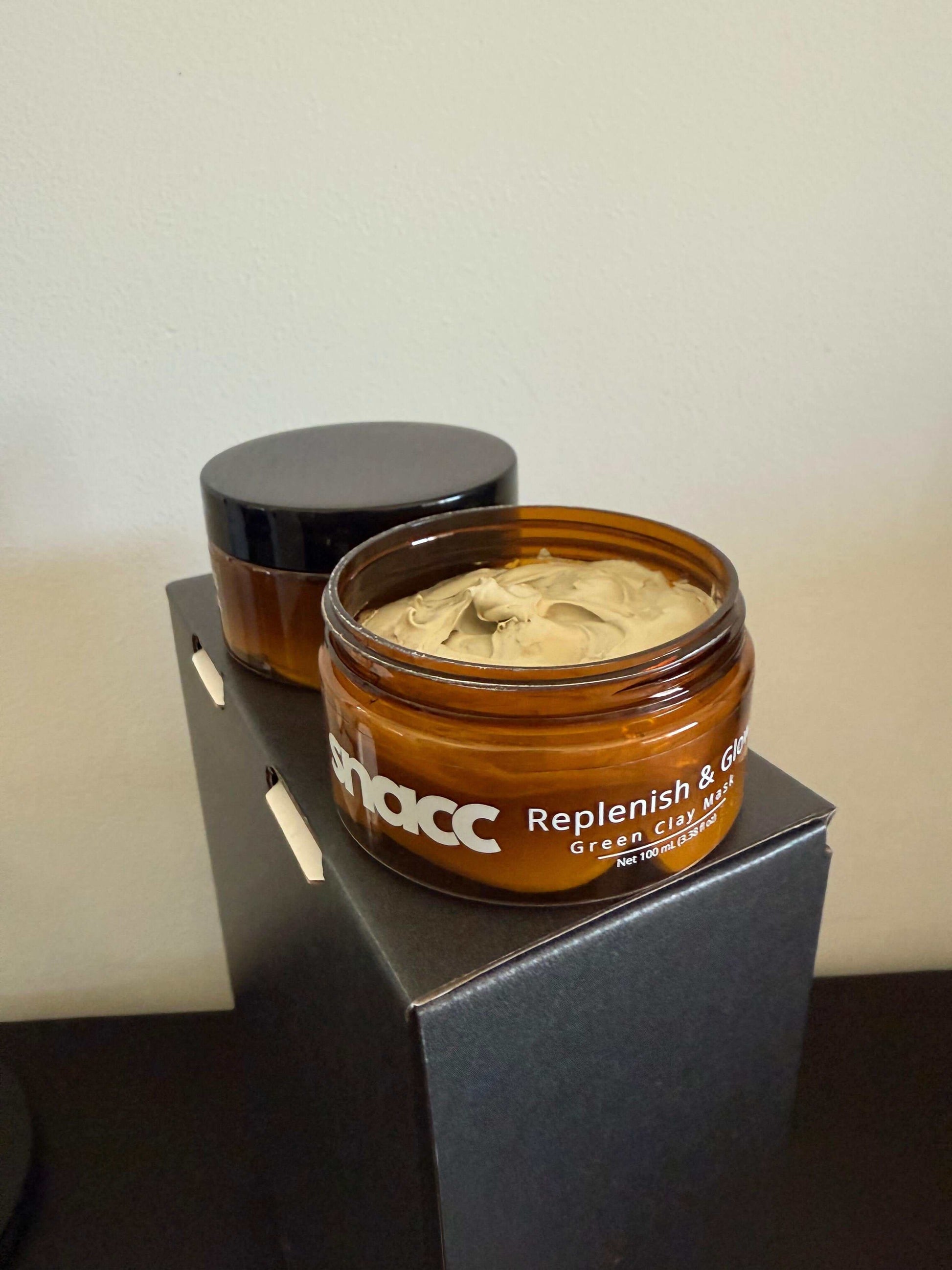 SNACC Beauty Replenish & Glow Green Clay Face Mask jar open on display, showing smooth green clay texture for purifying skincare.