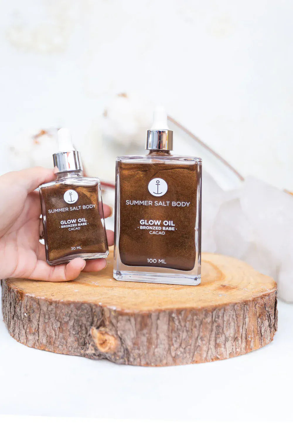 Summer Salt Body Bronzed Babe Glow Oil 100ml bottle displayed on a wooden surface, ideal for radiant skin with a bronzed glow.