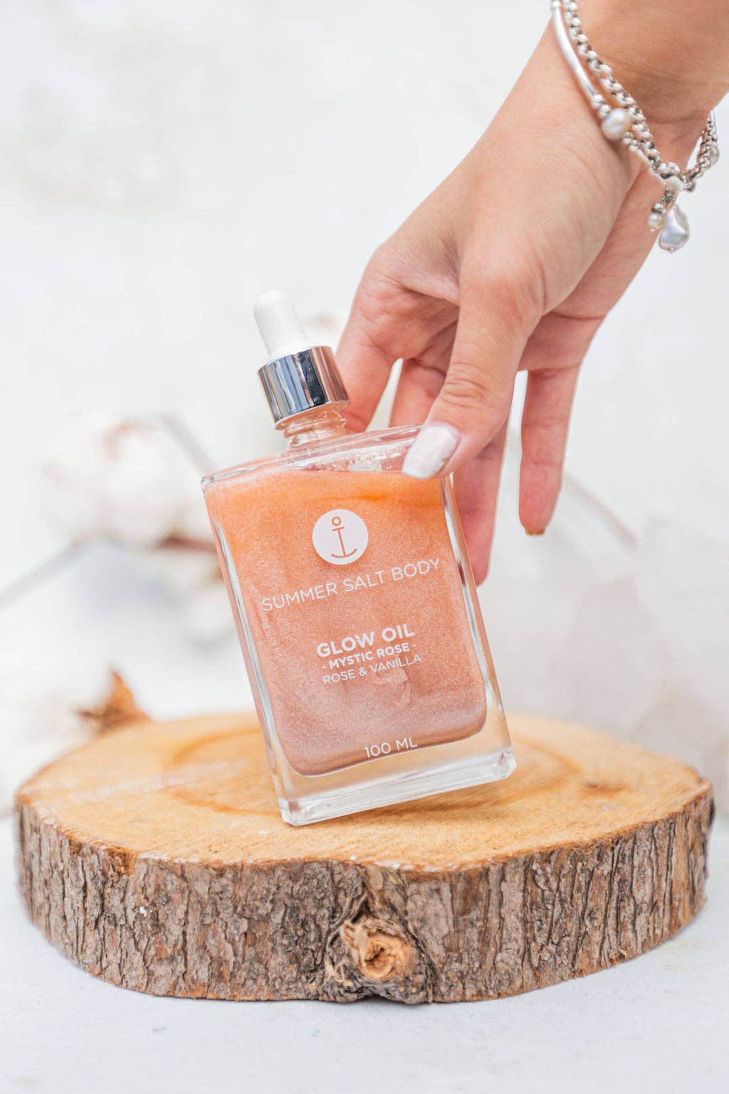 Summer Salt Body Mystic Rose Body Glow Oil 100ml bottle displayed outdoors on a wooden base.